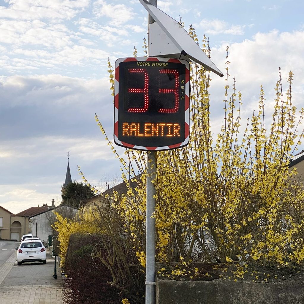 Radar pédagogique affichant 'Ralentir' en entrée de village pour le contrôle de vitesse aux abords d'une école
