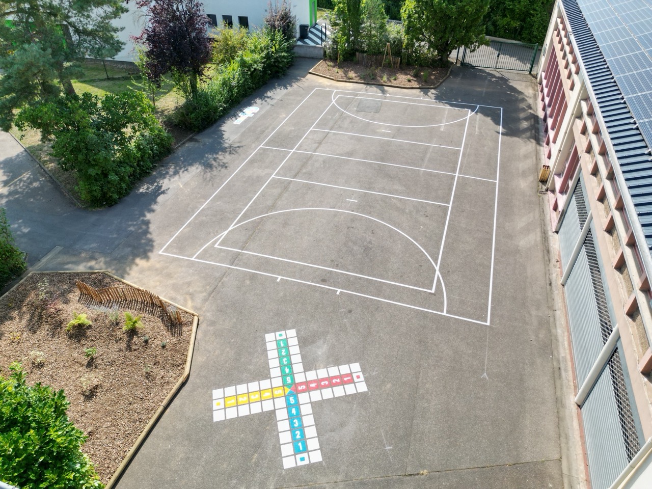 Vue drone d'une cour d'école avec terrain sportif coloré et marelle chiffres au sol à Hargarten-aux-Mines