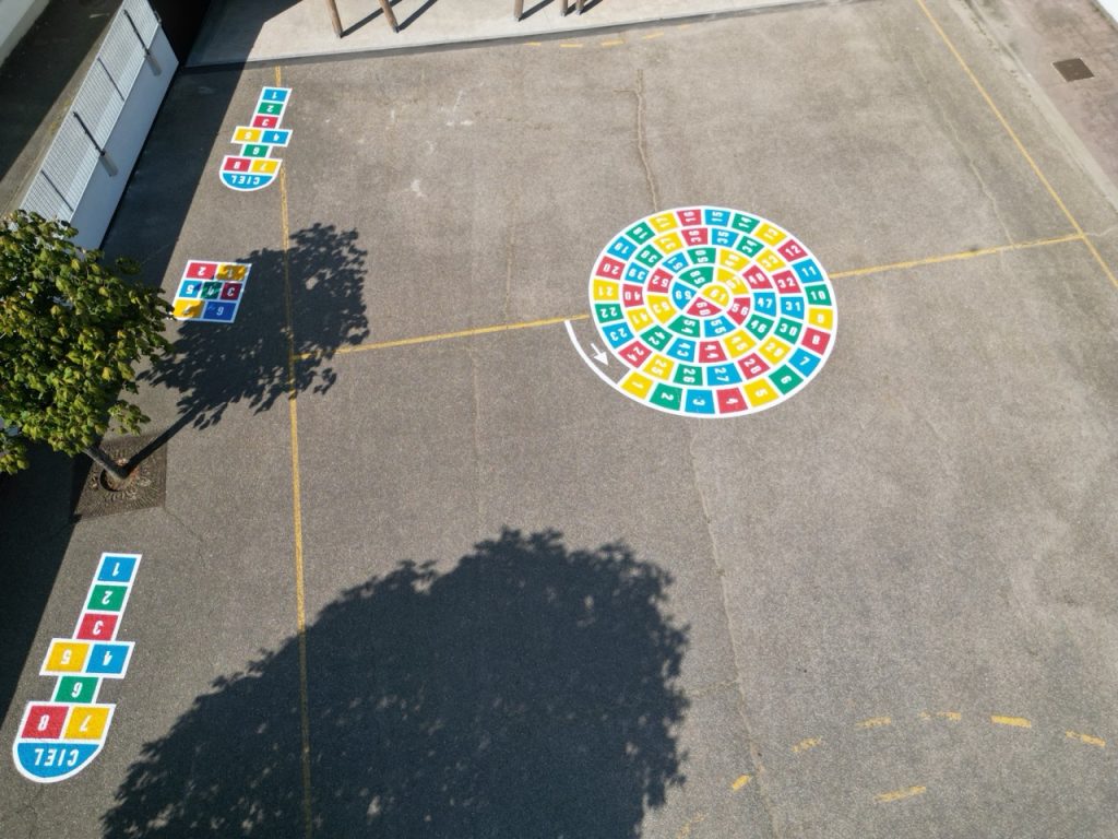 Vue drone d'une cour d'école avec escargot coloré numéroté et plusieurs marelles réalisés par C2 Marquage
