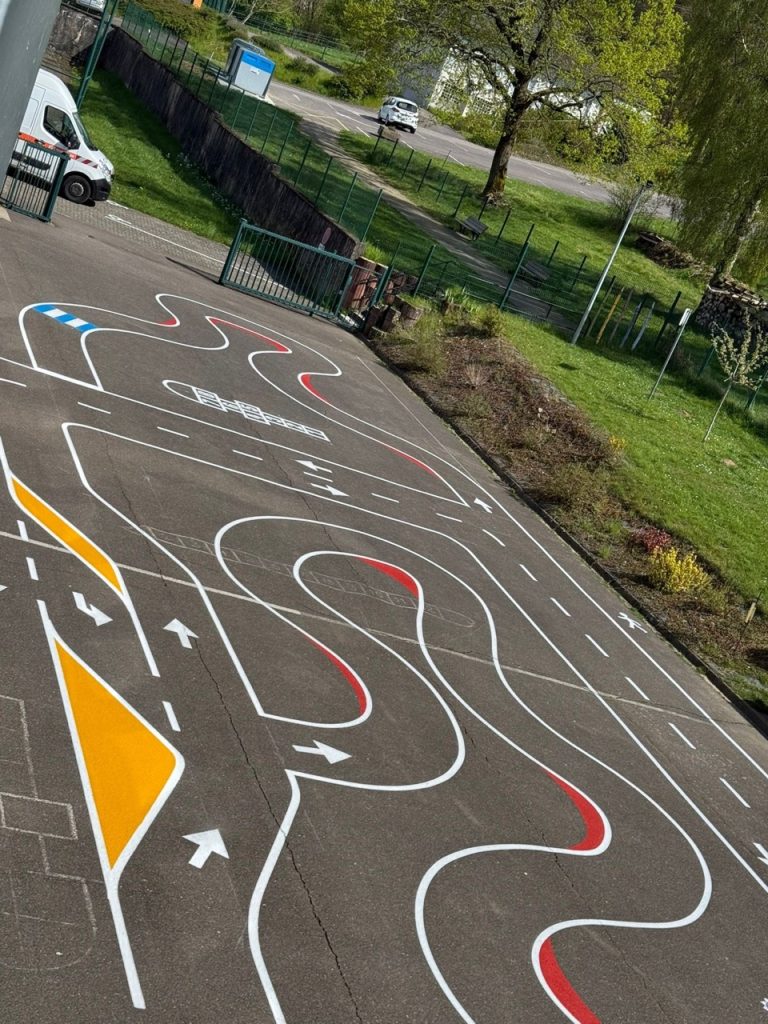 Piste pédagogique peinte au sol avec virages sinueux et marquages directionnels à l'école de Hargarten-aux-Mines