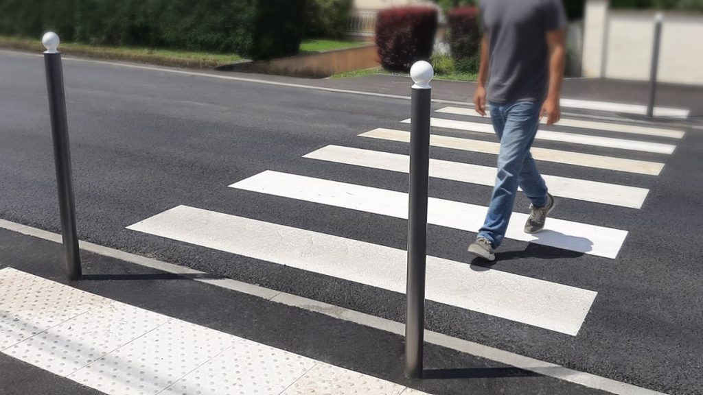 passage piéton accessible pmr avec bande d’éveil de vigilance et piéton en train de traverser