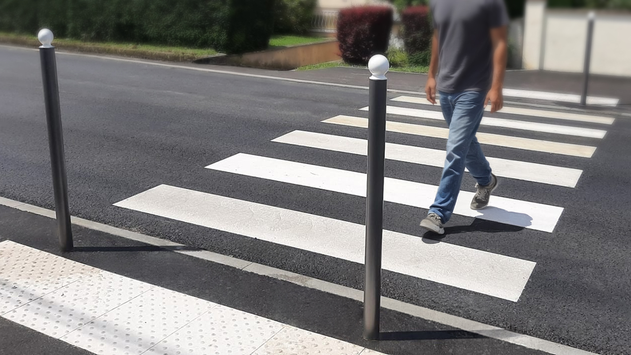 passage piéton accessible pmr avec bande d’éveil de vigilance et piéton en train de traverser