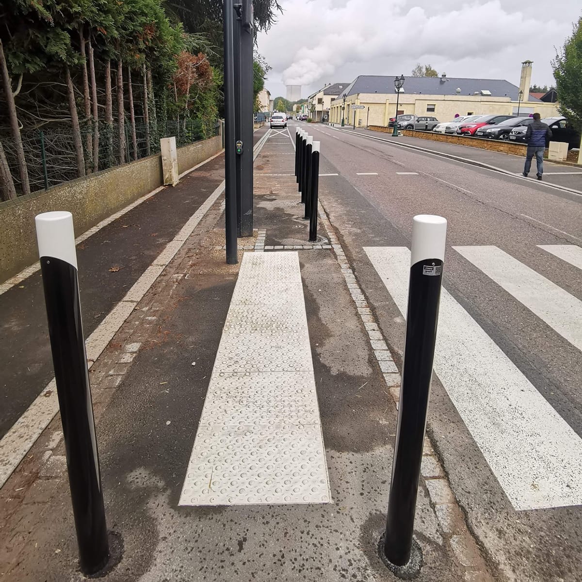 Potelets noirs et blancs lumineux disposés de part et d'autre d'un passage piéton avec bandes d'éveil podotactiles PMR