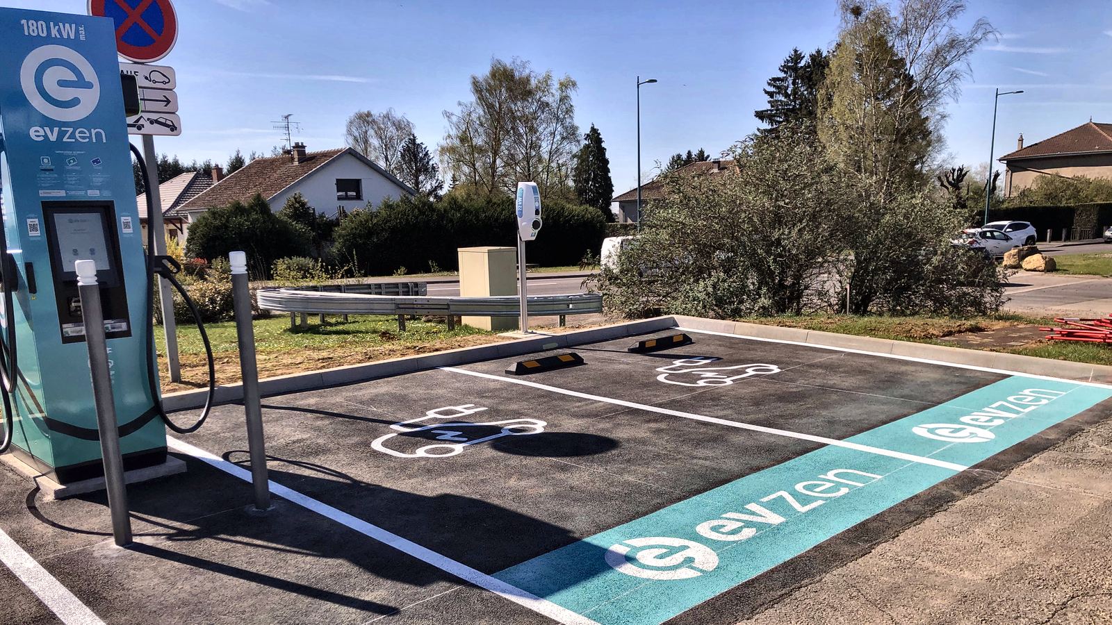 Place de stationnement réservée aux véhicules électriques avec marquage au sol vert et borne de recharge