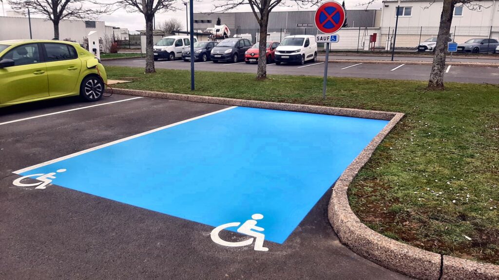 Place de stationnement réservée aux personnes à mobilité réduite (PMR) avec pictogramme blanc sur fond bleu
