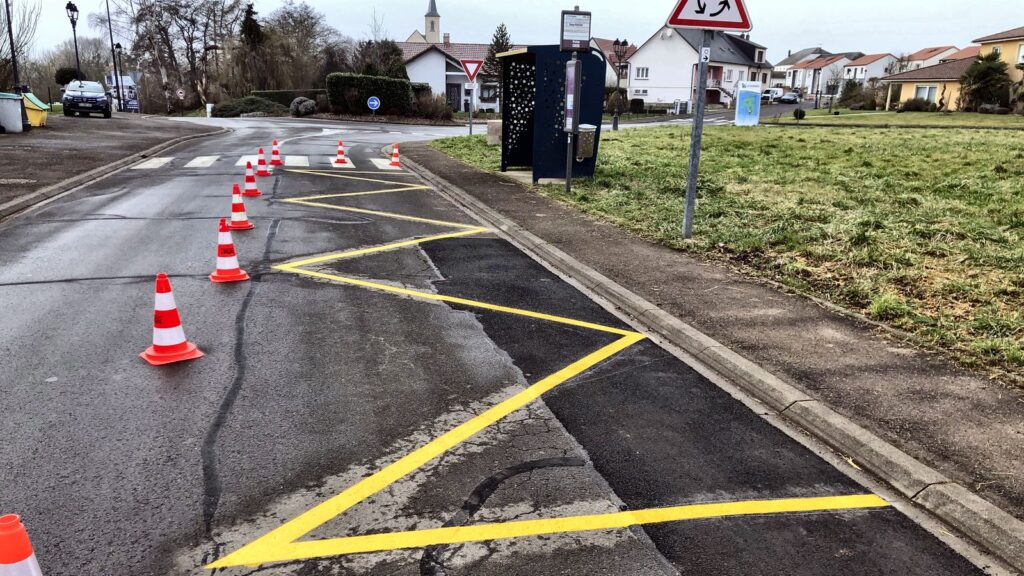 Marquage au sol jaune en zigzag délimitant un arrêt de bus, interdisant le stationnement aux autres usagers