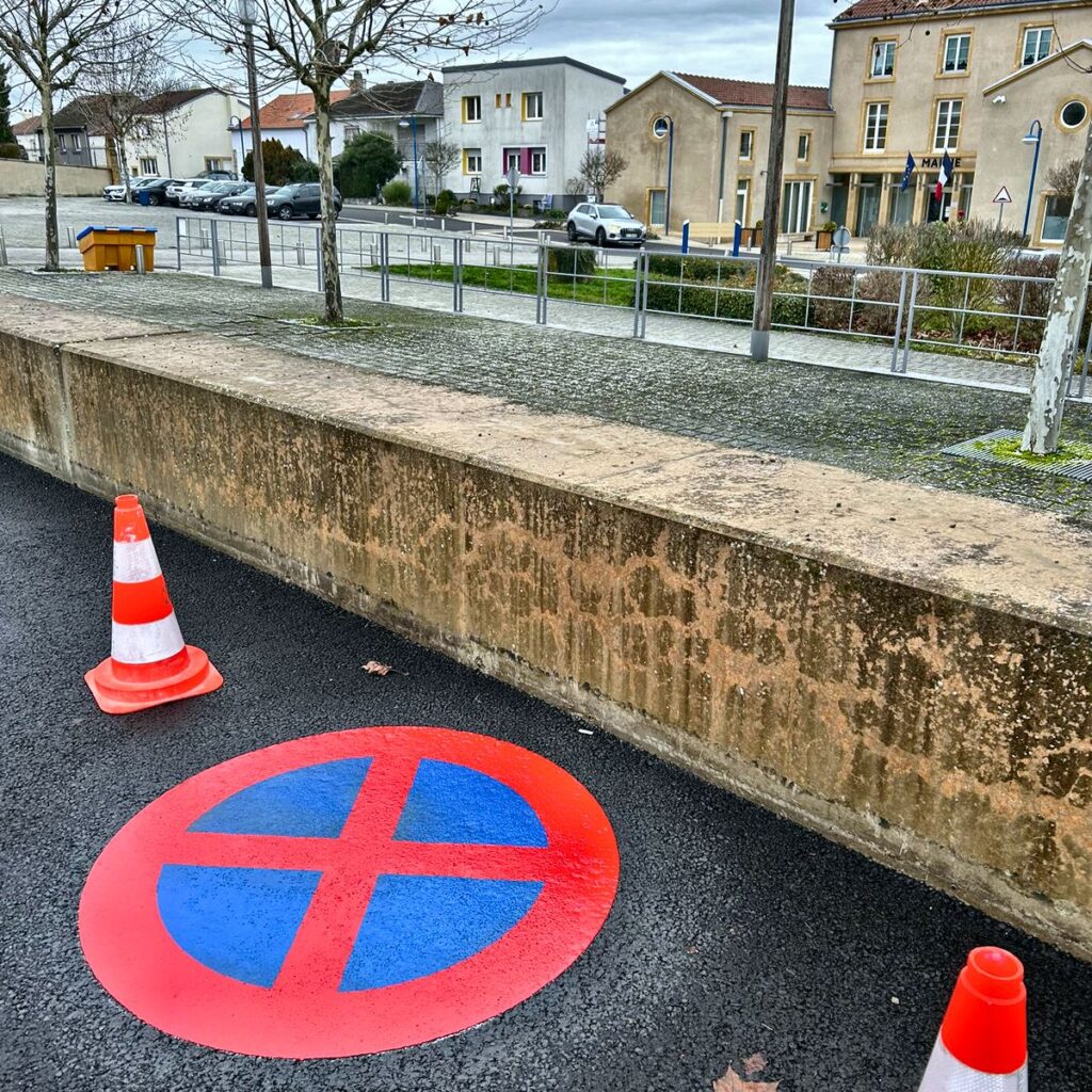 Marquage rouge au sol signalant l'interdiction de stationnement et d'arrêt sur une voie d'accès privée