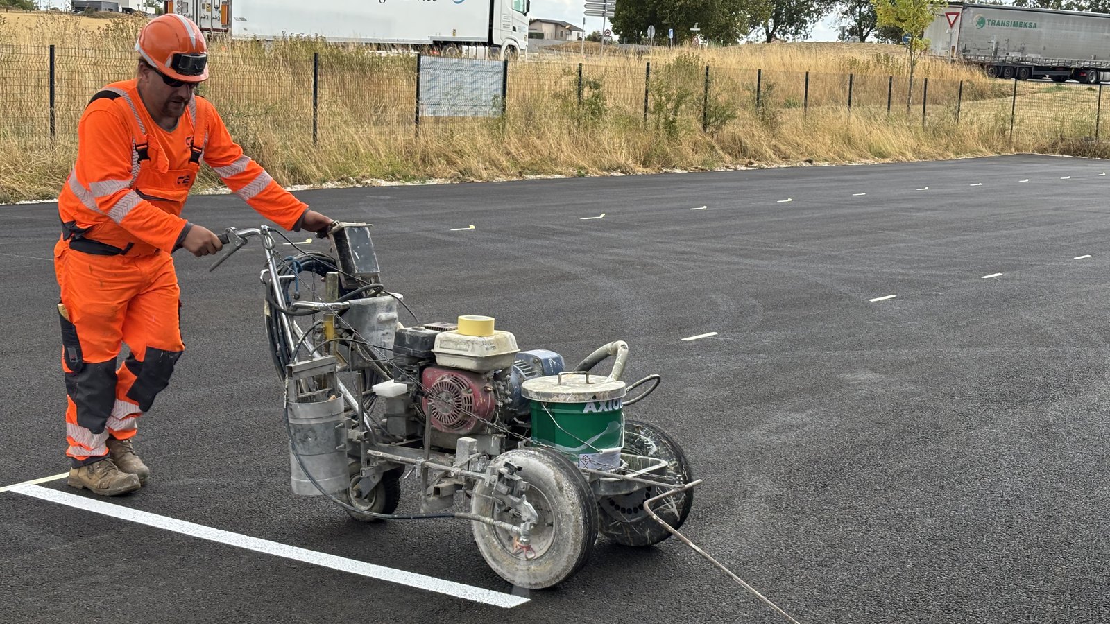 Applicateur C2 MARQUAGE traçant une ligne blanche à la machine de marquage airless sur un parking neuf.