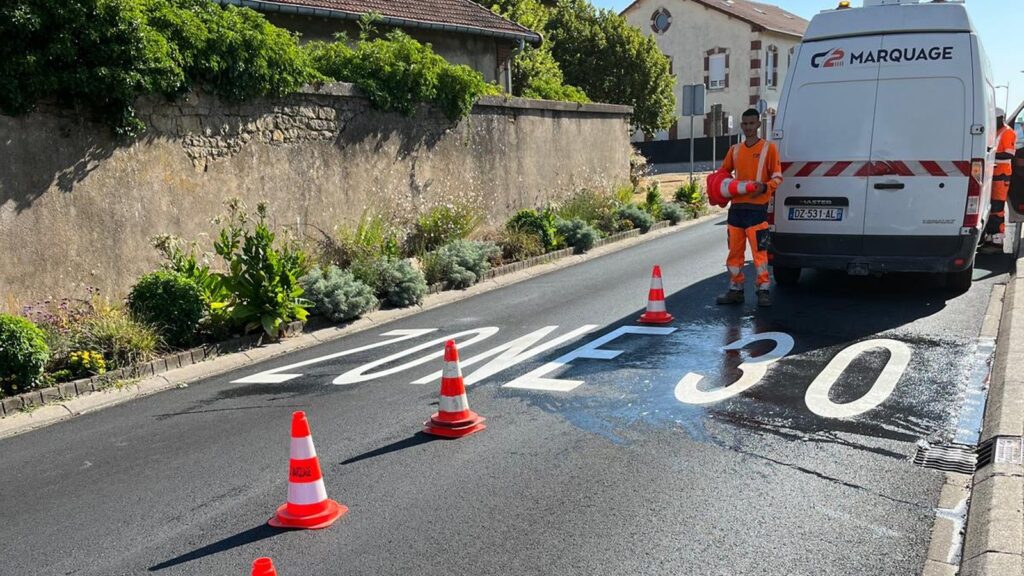 Équipe C2 MARQUAGE appliquant une inscription « ZONE 30 » sur la chaussée