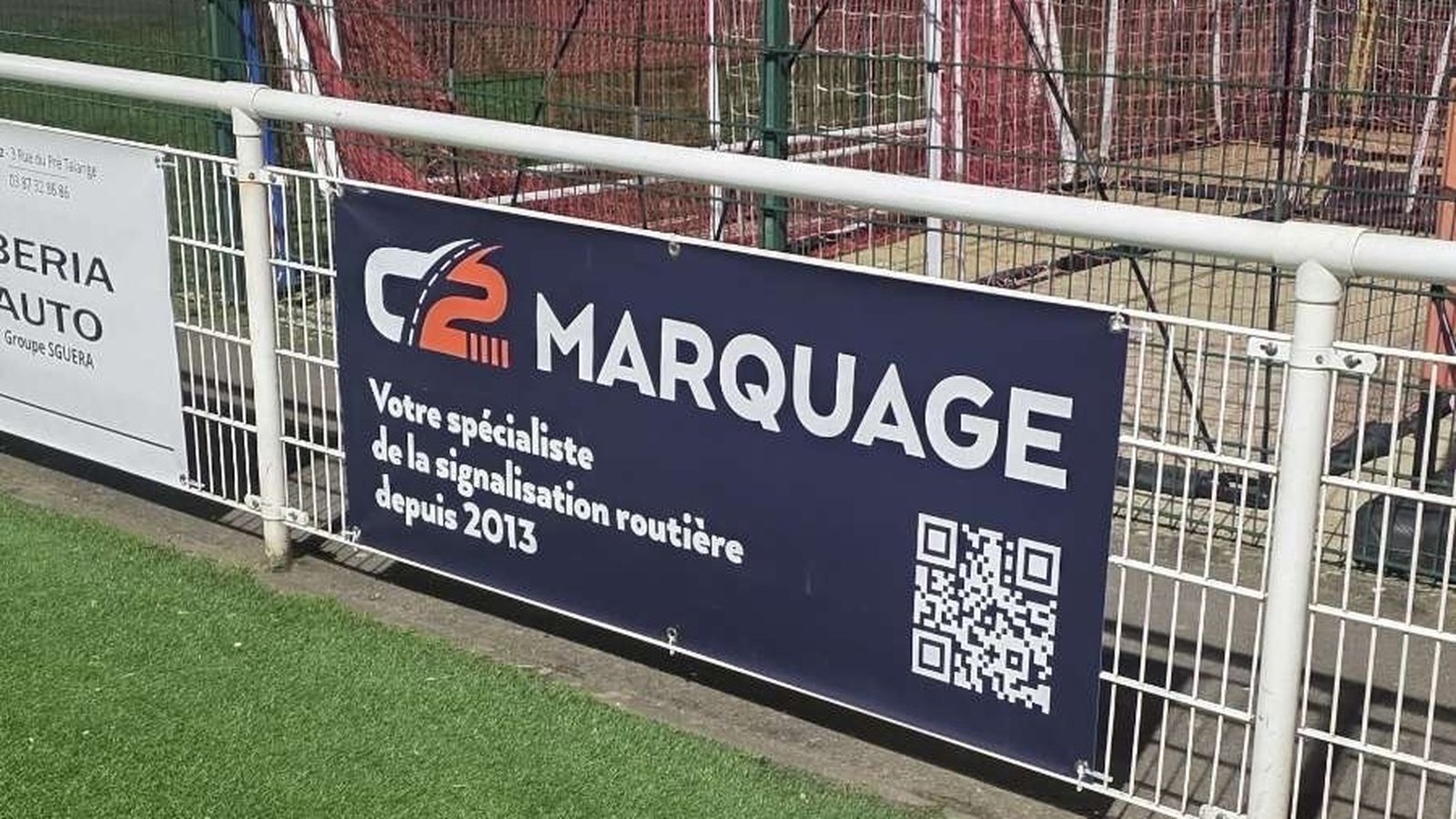 Panneau du sponsor C2 MARQUAGE installé au bord du terrain de football de Marange-Silvange