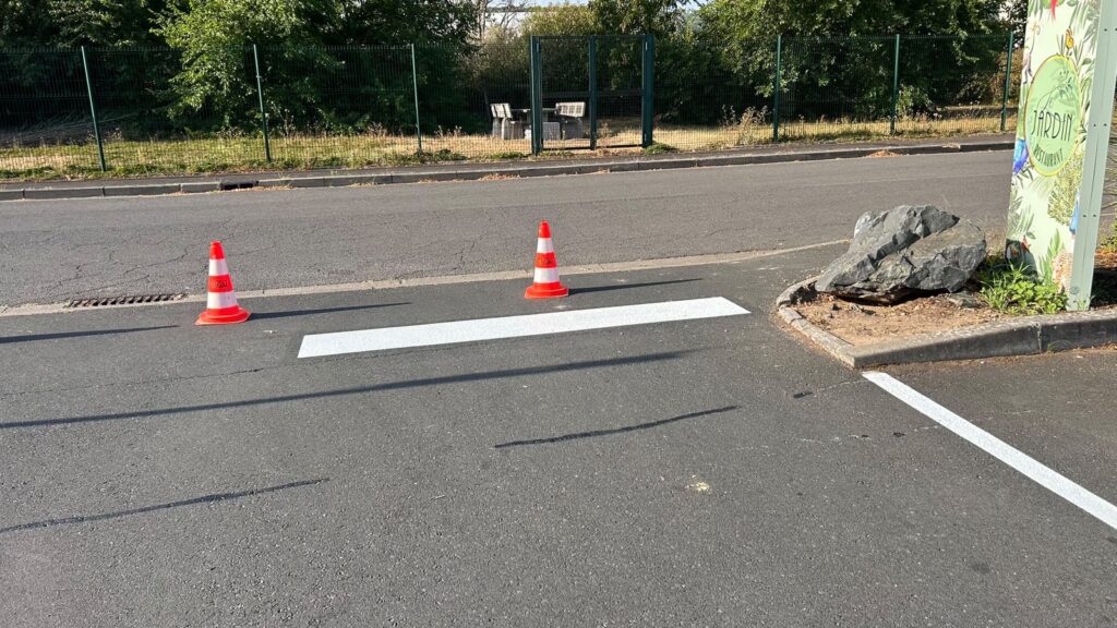 Application de peinture routière blanche sur le parking du restaurant Le Jardin à Jouy-aux-Arches en Moselle.