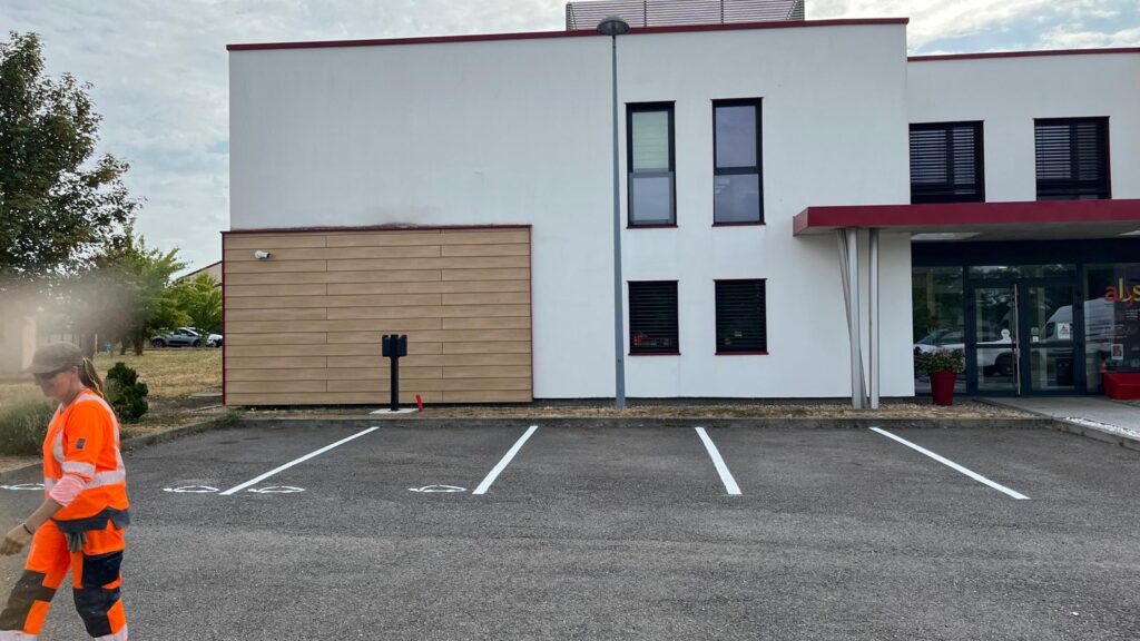 Parking rénové devant le siège mosellan d'ALYS à Ennery, avec des places clairement délimitées.