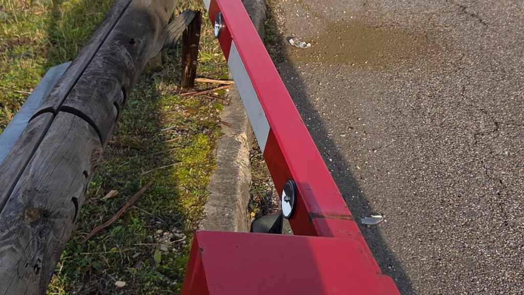 Vue rapprochée de l'ancienne barrière rouge déformée après un accident sur un parking commercial