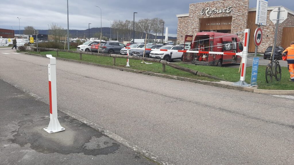 Barrière manuelle d'accès installée sur de nouveaux massifs béton à l'entrée d'un parking